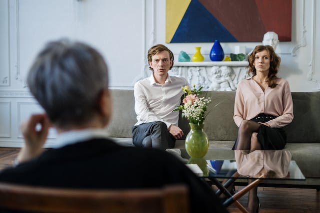 man and woman sitting on couch talking with third party